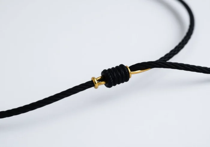 Showcasing a stylish zota bransoletka na sznurku with gold pendants on a black cord,
